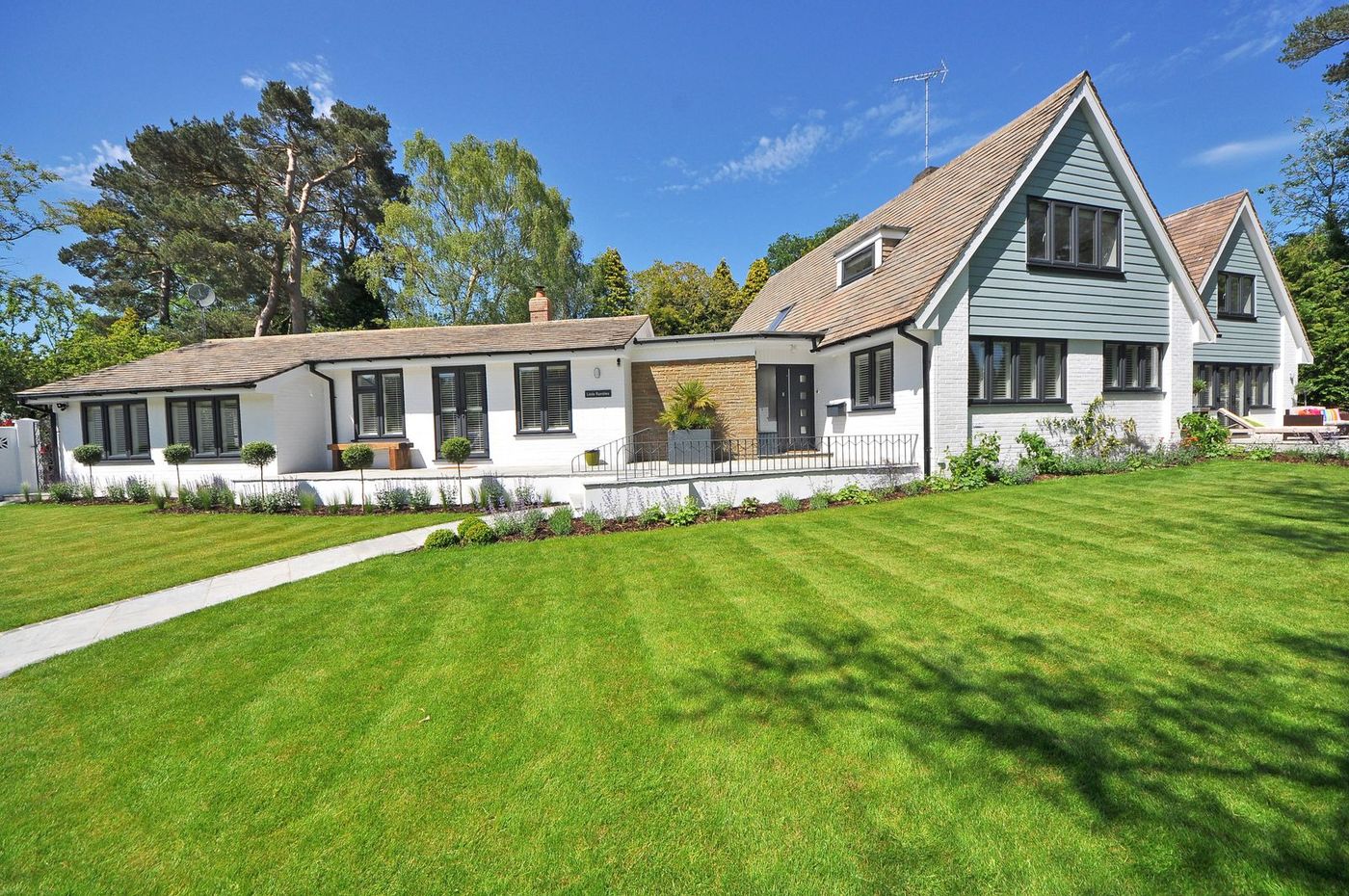 House with a large mown lawn and planted borders